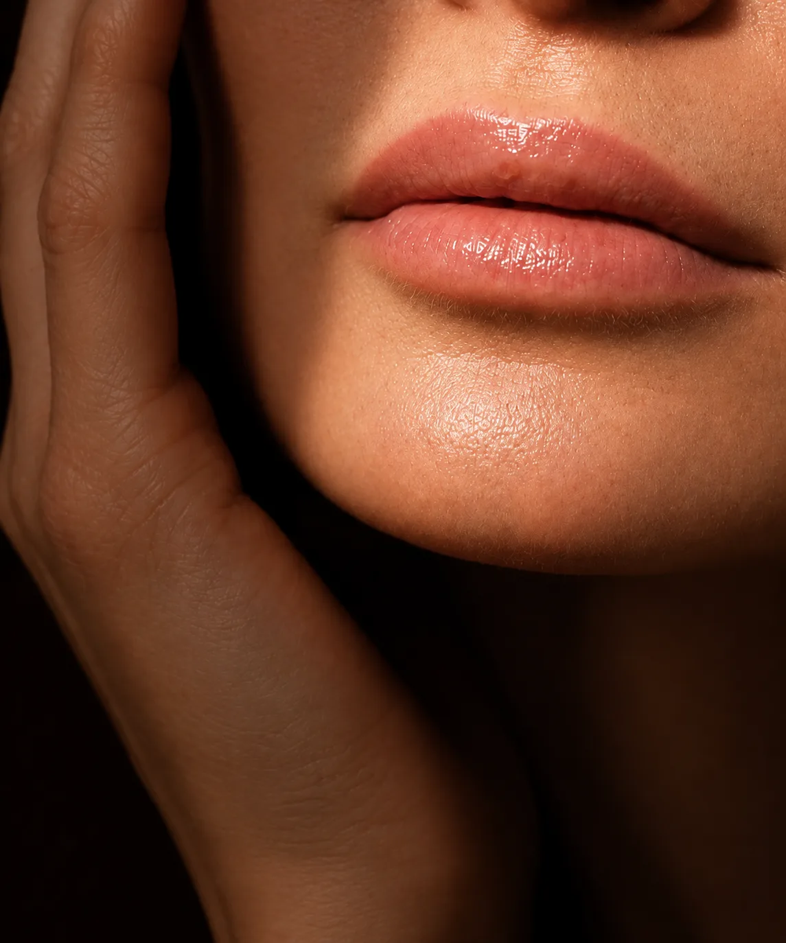 Close-up of lips and hands framing the jaw